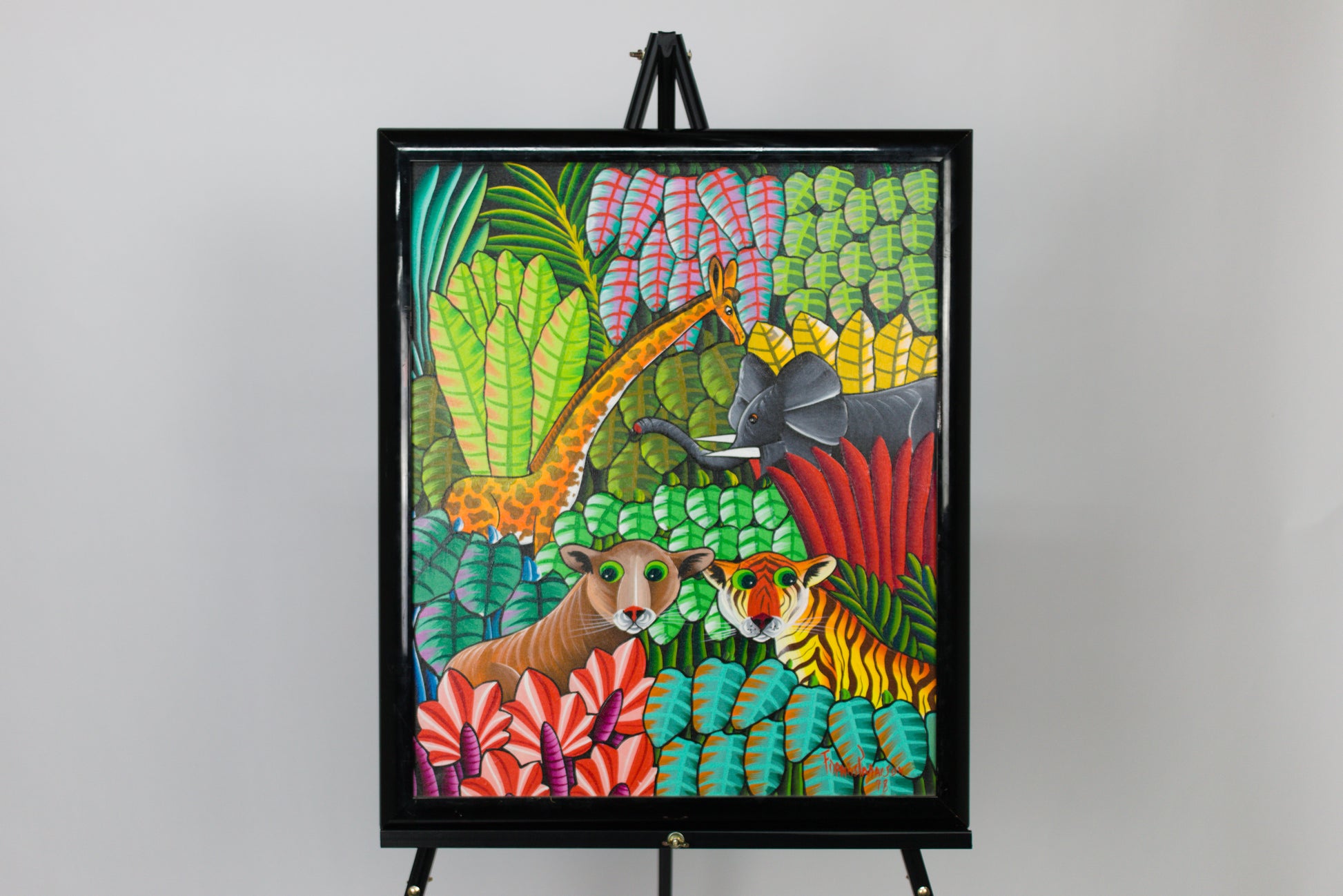 Colorful artwork of animals in a jungle scene on an easel against a gray background