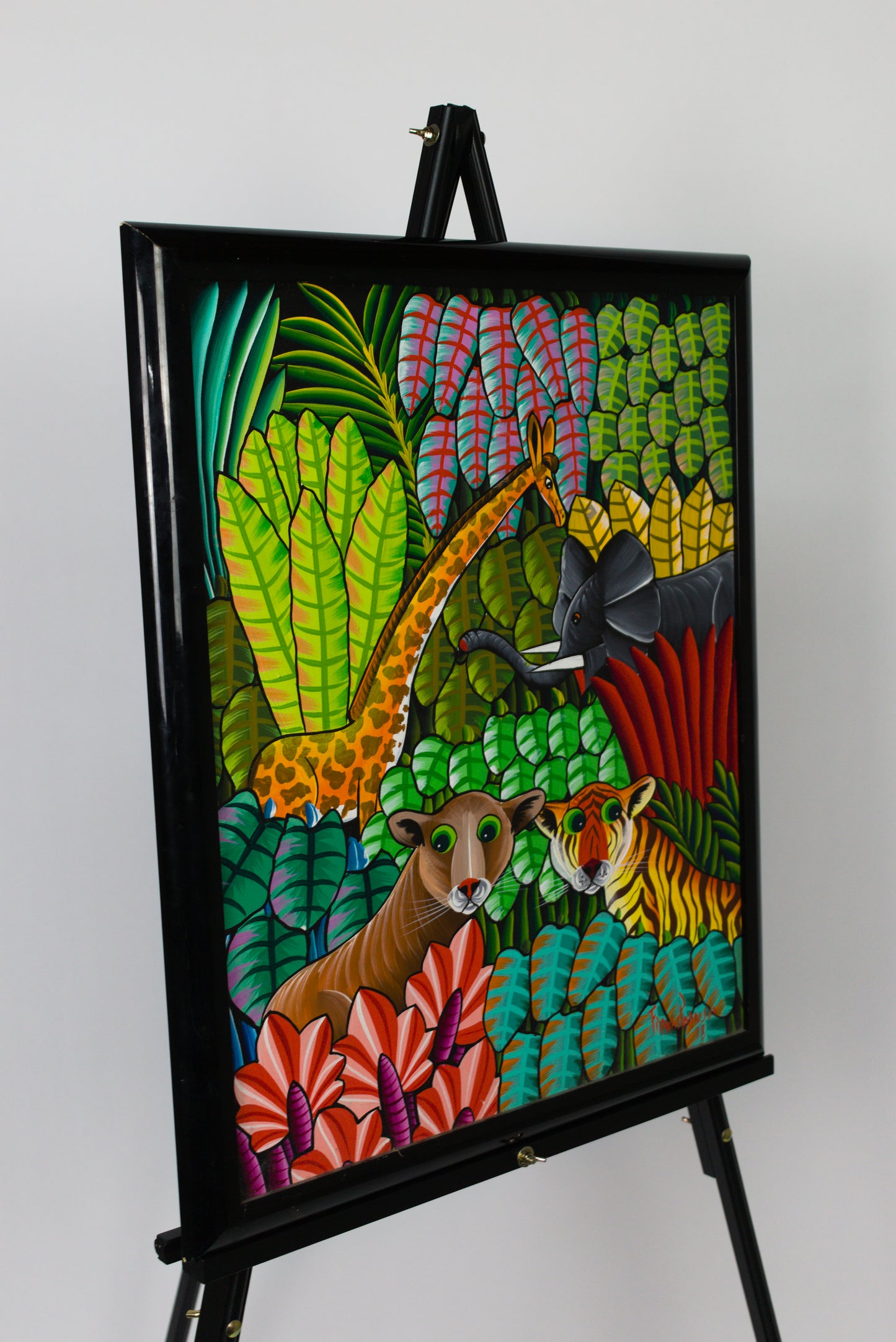Colorful artwork of animals in a jungle setting on an easel against a white background