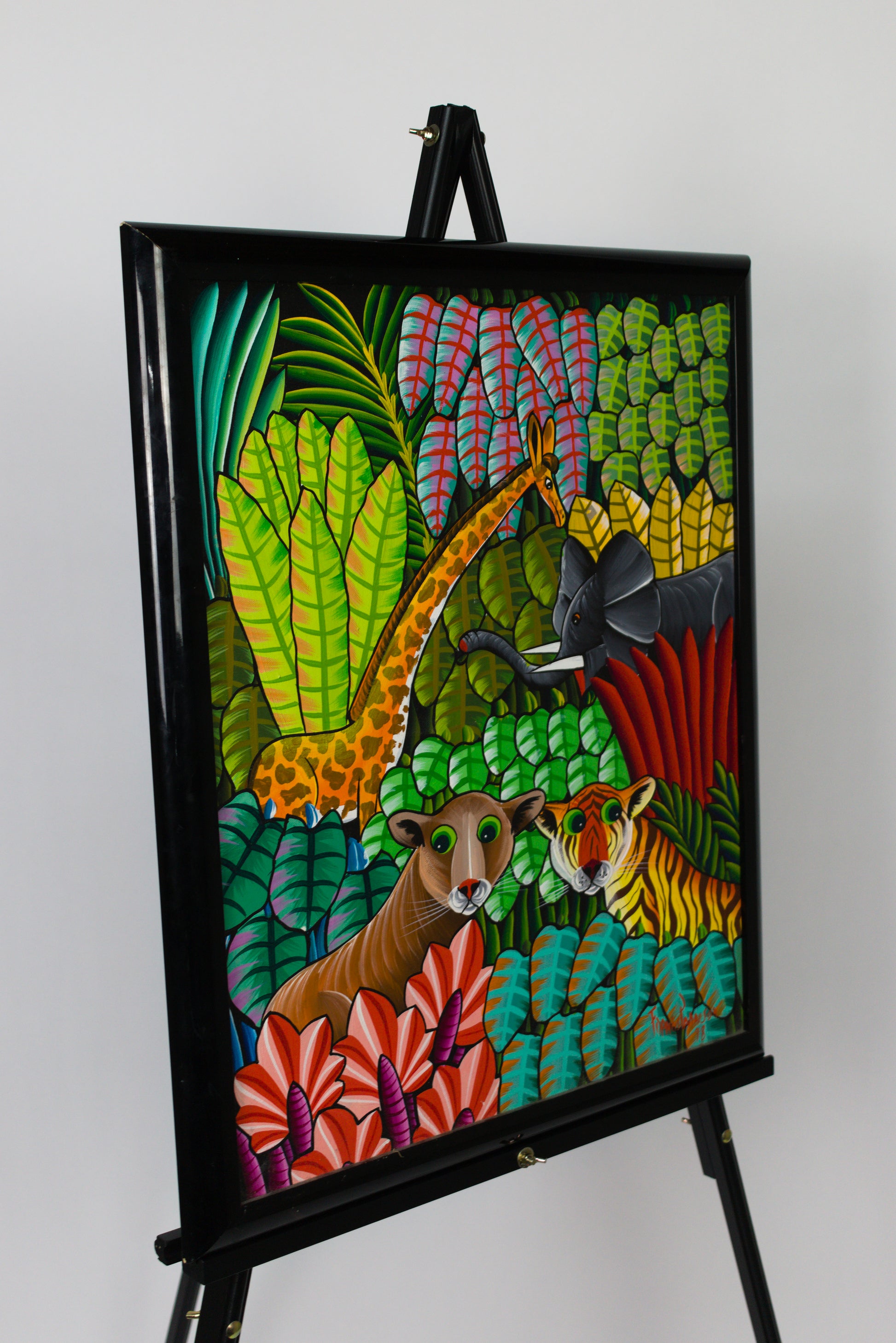Colorful artwork of animals in a jungle setting on an easel against a white background